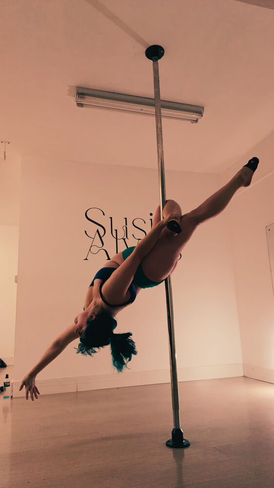 Professora Tiffany em um movimento acrobático na barra de pole